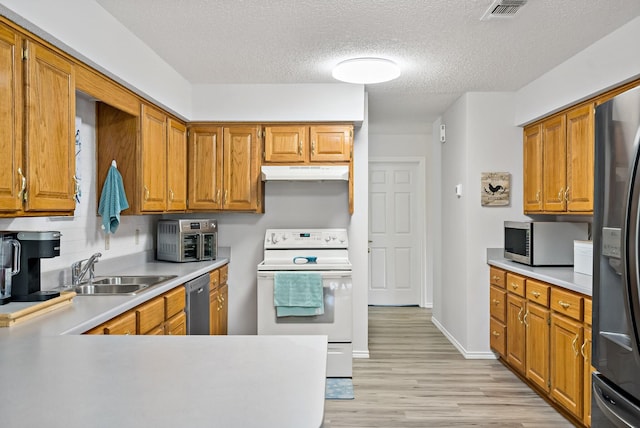 kitchen with appliances with stainless steel finishes, sink, a textured ceiling, and light hardwood / wood-style flooring