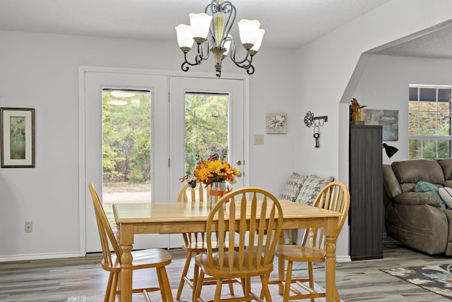 dining room with light hardwood / wood-style floors, a textured ceiling, and a notable chandelier