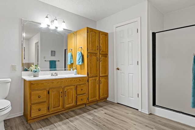 bathroom featuring hardwood / wood-style flooring, an enclosed shower, vanity, a textured ceiling, and toilet