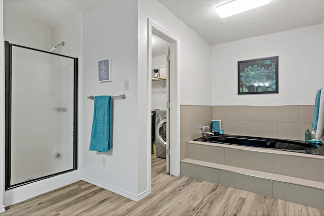 bathroom featuring separate shower and tub, washer / dryer, hardwood / wood-style floors, and a textured ceiling