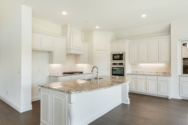 kitchen with a center island with sink, appliances with stainless steel finishes, sink, white cabinetry, and dark hardwood / wood-style floors