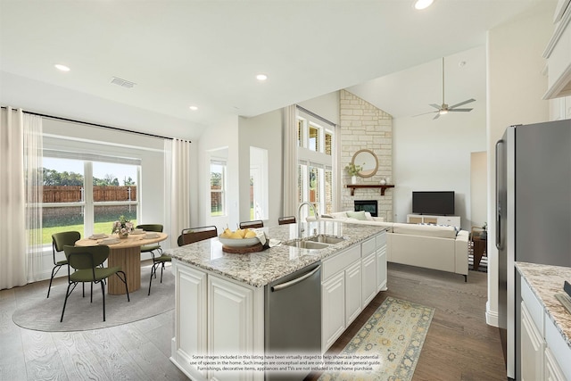 kitchen with sink, dark hardwood / wood-style flooring, stainless steel appliances, white cabinets, and a center island with sink