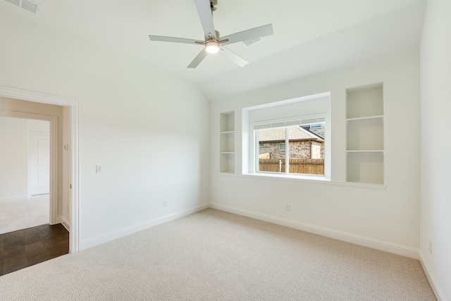 empty room with hardwood / wood-style flooring, ceiling fan, built in features, and vaulted ceiling