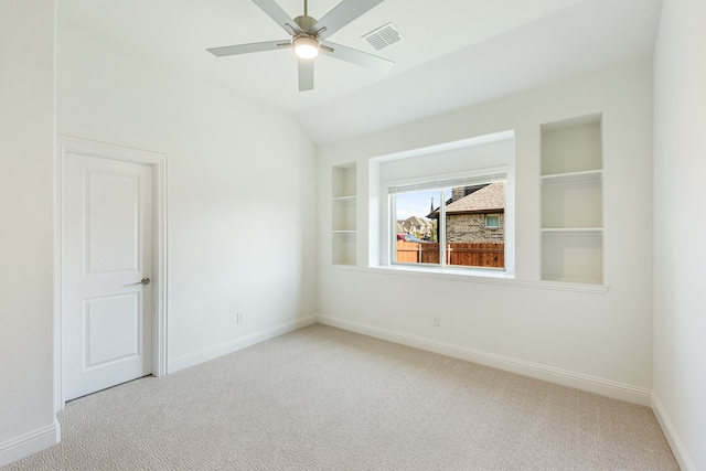 carpeted spare room with lofted ceiling, built in features, and ceiling fan