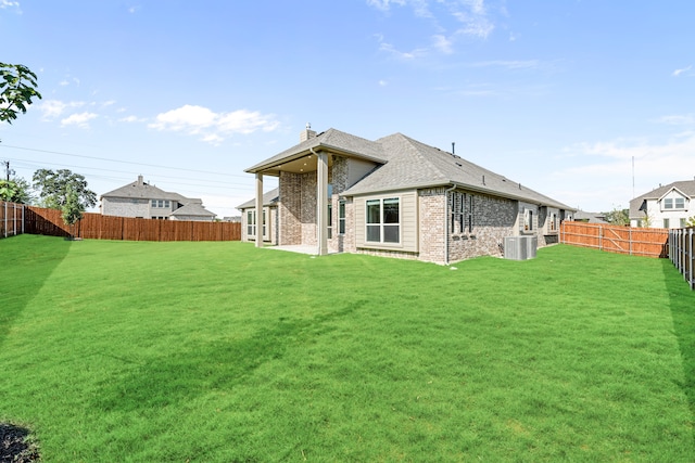 rear view of property featuring a yard, a patio area, and central AC