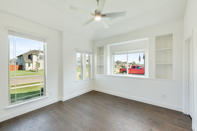 spare room with dark wood-type flooring, ceiling fan, and built in features