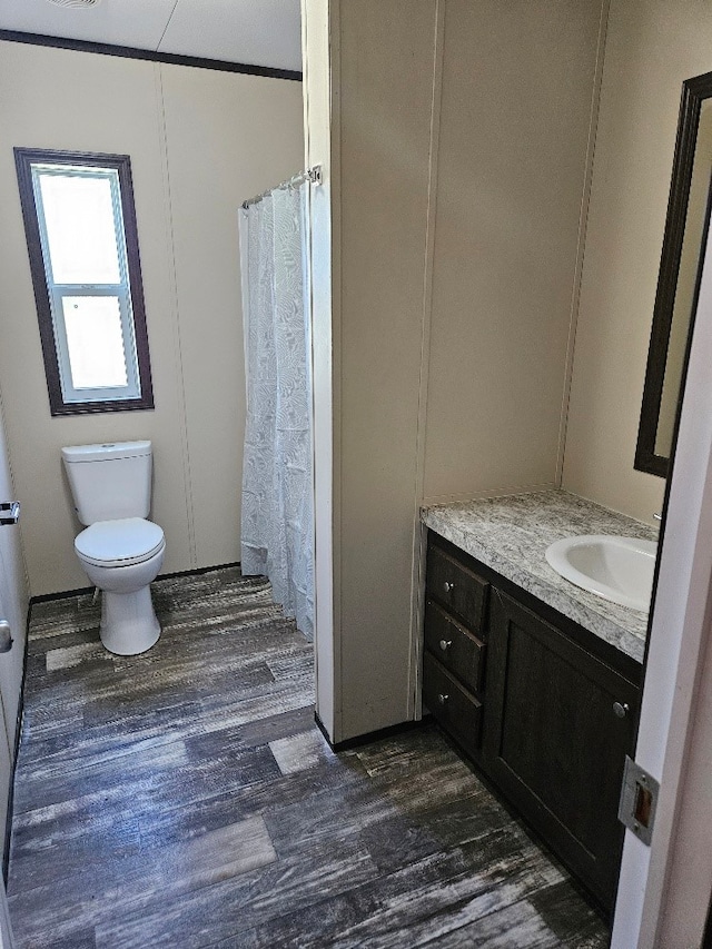 full bath with curtained shower, wood finished floors, toilet, and vanity