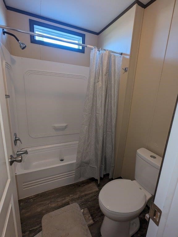 bathroom with hardwood / wood-style floors, shower / tub combo, and toilet