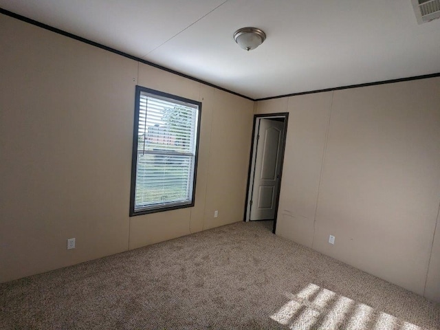 carpeted empty room featuring ornamental molding and visible vents