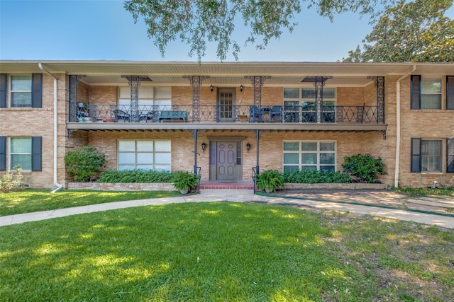 view of front of property with a front yard and a balcony