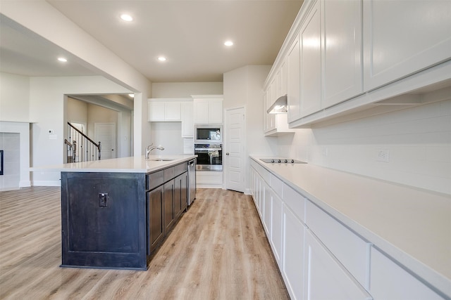 kitchen featuring a kitchen island with sink, white cabinets, sink, light hardwood / wood-style flooring, and stainless steel appliances