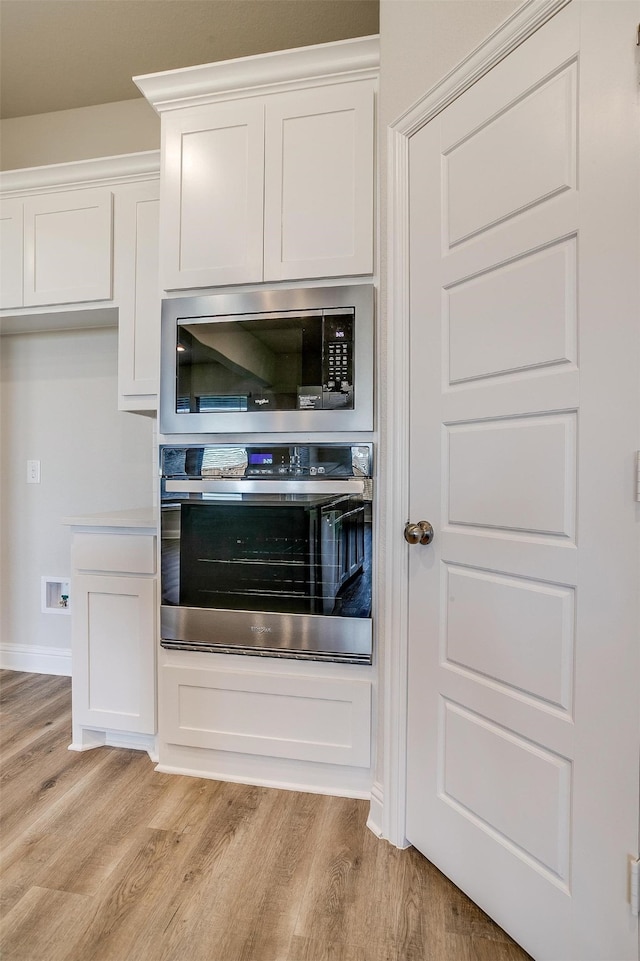 kitchen with white cabinetry, light hardwood / wood-style flooring, and stainless steel appliances