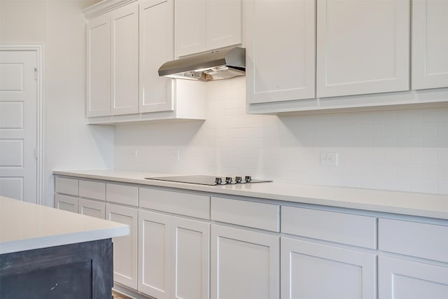 kitchen featuring tasteful backsplash, black electric cooktop, white cabinetry, and range hood