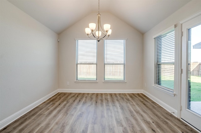 spare room featuring plenty of natural light, light wood-type flooring, and vaulted ceiling