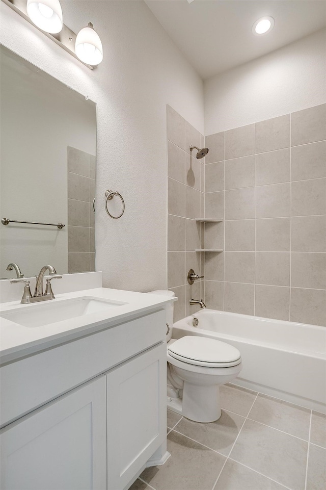 full bathroom featuring tile patterned flooring, vanity, tiled shower / bath combo, and toilet