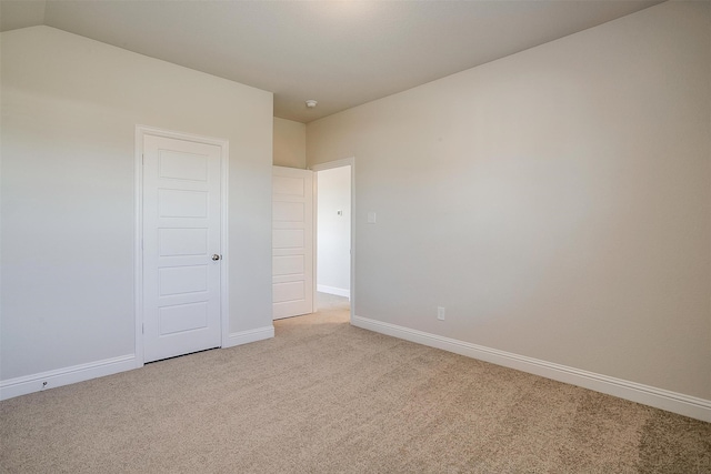 spare room with light colored carpet and vaulted ceiling