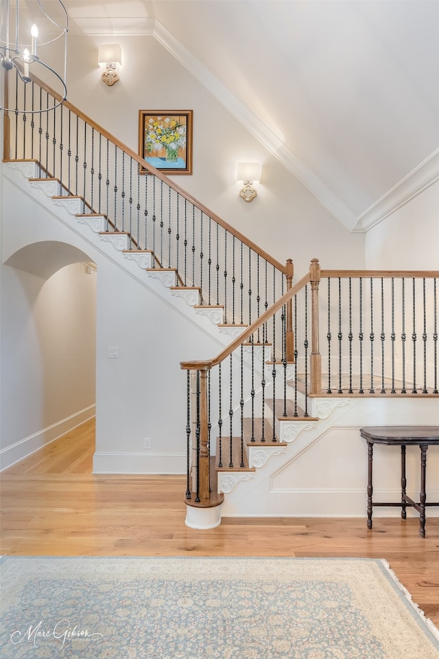 stairs featuring hardwood / wood-style flooring, crown molding, and high vaulted ceiling