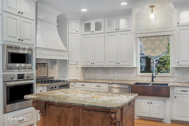 kitchen with tasteful backsplash, stainless steel appliances, sink, a center island, and white cabinetry