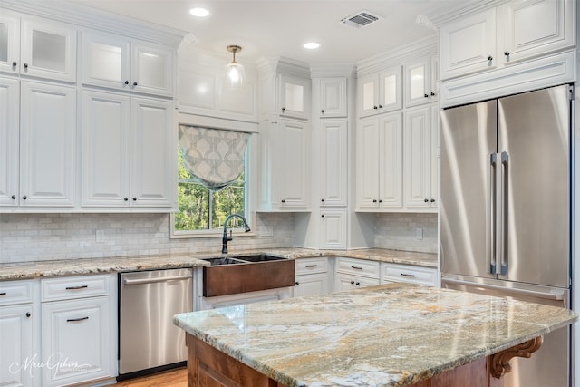 kitchen featuring backsplash, white cabinets, hanging light fixtures, light stone countertops, and appliances with stainless steel finishes