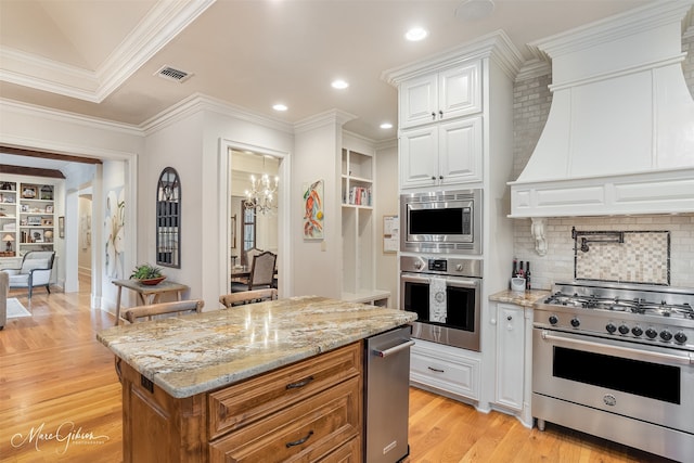 kitchen featuring decorative backsplash, custom exhaust hood, stainless steel appliances, white cabinets, and light hardwood / wood-style floors