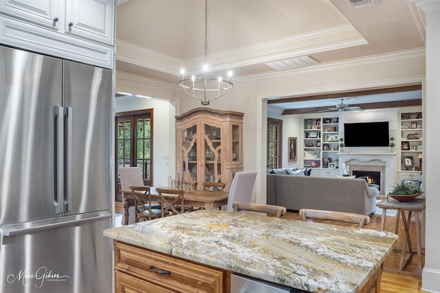 kitchen featuring ceiling fan with notable chandelier, light stone counters, light wood-type flooring, and high quality fridge