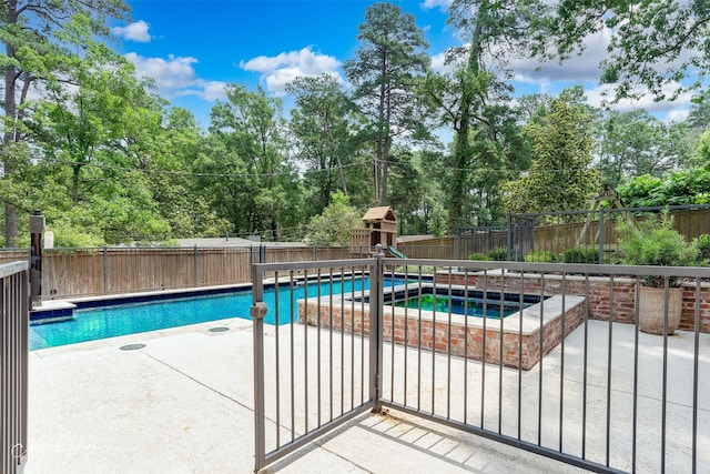 view of swimming pool with an in ground hot tub, a playground, and a patio area