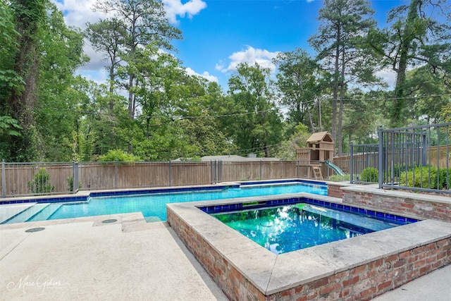 view of swimming pool with an in ground hot tub and a playground