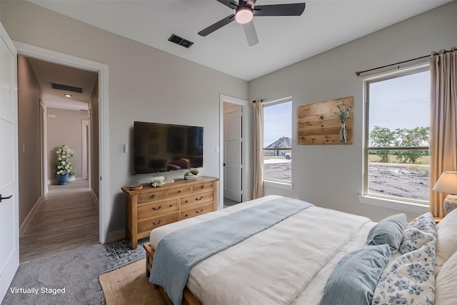 bedroom featuring ceiling fan, wood-type flooring, and multiple windows