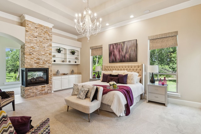 carpeted bedroom featuring an inviting chandelier, ornamental molding, a stone fireplace, and multiple windows