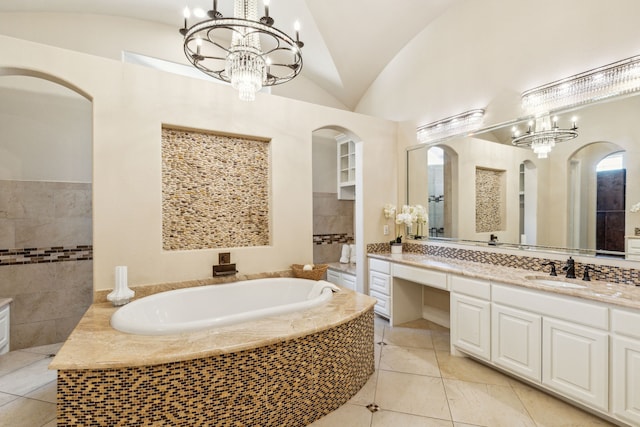 bathroom with vaulted ceiling, a relaxing tiled tub, a notable chandelier, and vanity