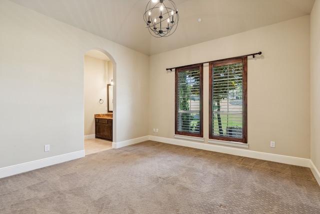 carpeted spare room featuring an inviting chandelier