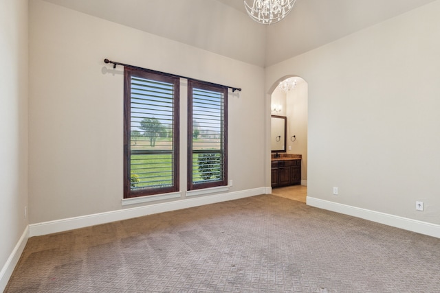 spare room with light carpet and an inviting chandelier