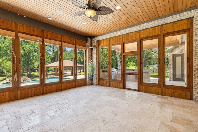 unfurnished sunroom featuring wooden ceiling and ceiling fan