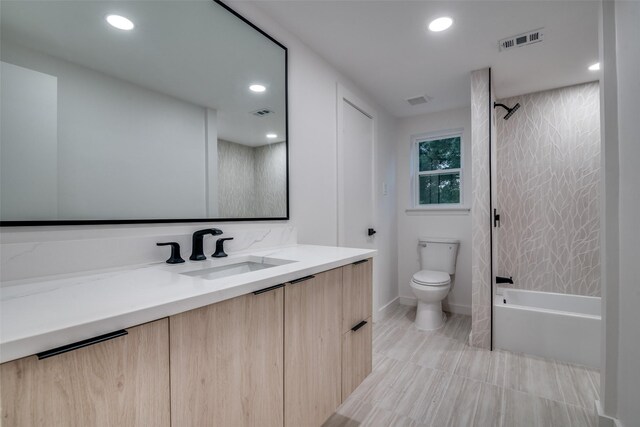 full bathroom featuring vanity, tiled shower / bath combo, and toilet