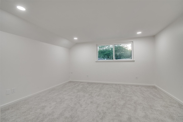 unfurnished room with vaulted ceiling and light colored carpet