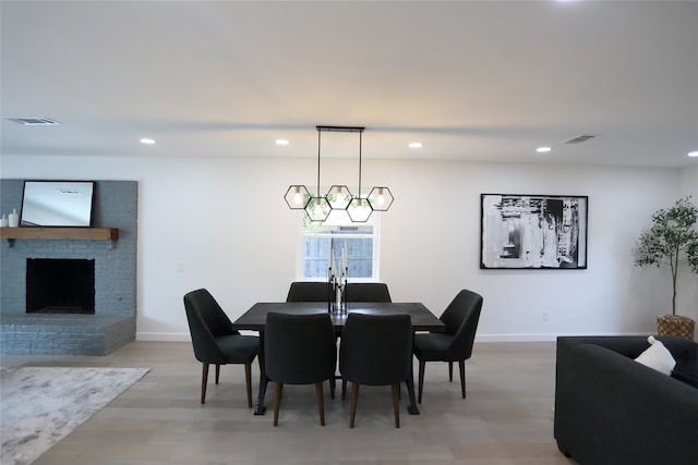 dining area with french doors, an inviting chandelier, light hardwood / wood-style floors, and a brick fireplace