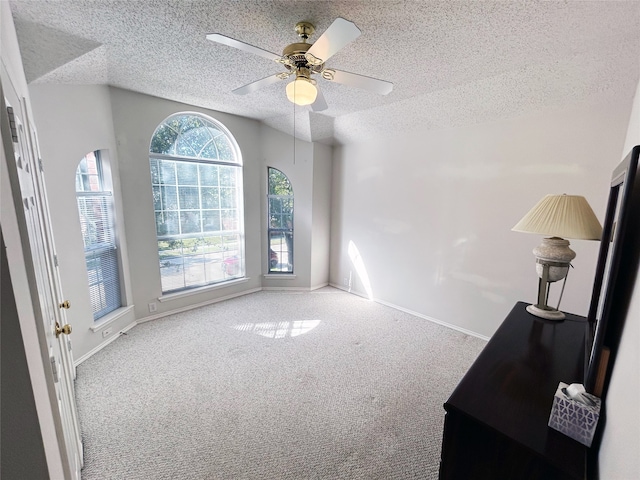 spare room featuring ceiling fan, light colored carpet, and a textured ceiling