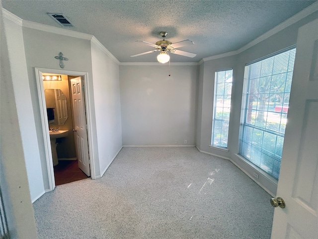 carpeted spare room featuring ceiling fan, a textured ceiling, and ornamental molding