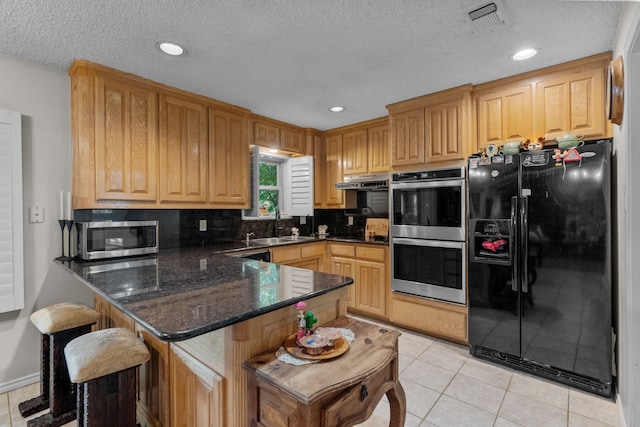 kitchen featuring tasteful backsplash, stainless steel appliances, kitchen peninsula, light tile patterned floors, and dark stone countertops