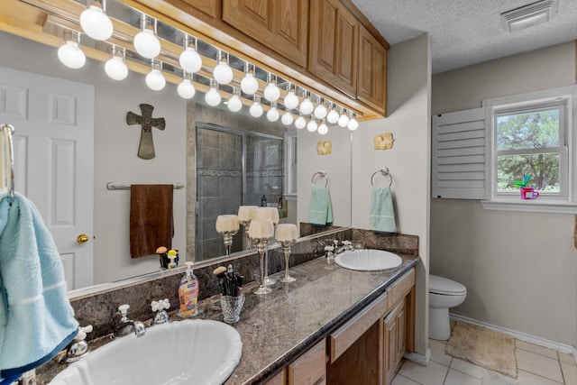 bathroom featuring toilet, tile patterned floors, a textured ceiling, and double vanity