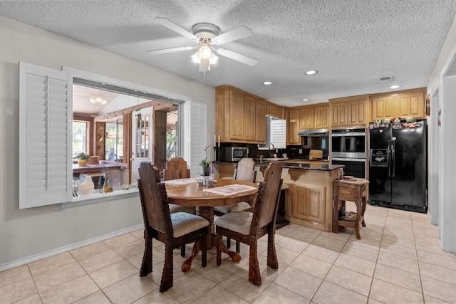 dining space featuring a textured ceiling, sink, light tile patterned floors, and ceiling fan