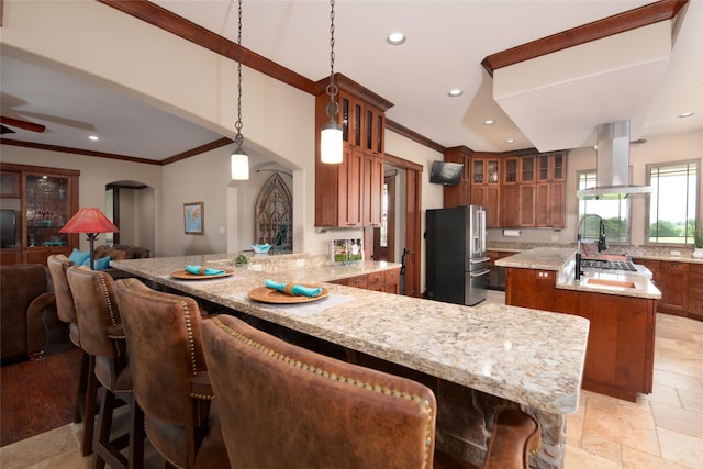 kitchen featuring kitchen peninsula, stainless steel fridge, pendant lighting, range hood, and a center island