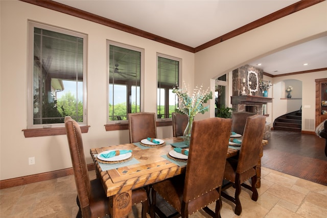 tiled dining space featuring ornamental molding and a large fireplace