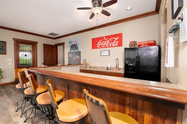 bar with light hardwood / wood-style floors, ornamental molding, refrigerator, and ceiling fan