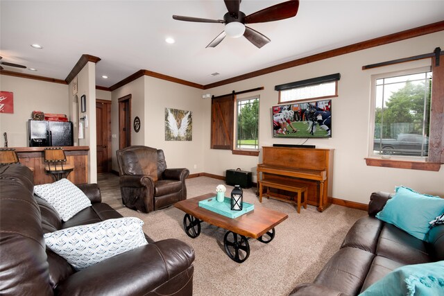 carpeted living room with a barn door, crown molding, and ceiling fan