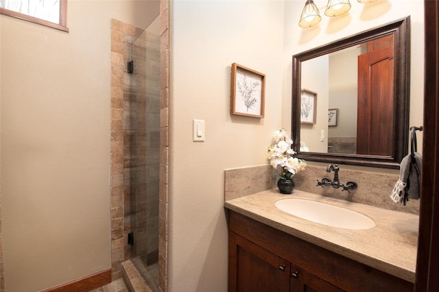 bathroom featuring a shower with door and vanity