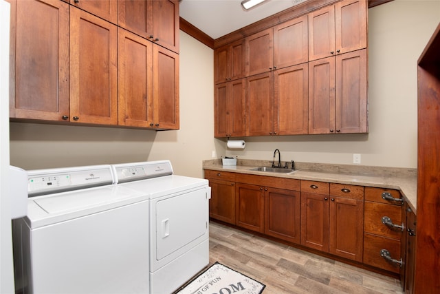 washroom with cabinets, ornamental molding, washer and clothes dryer, light wood-type flooring, and sink