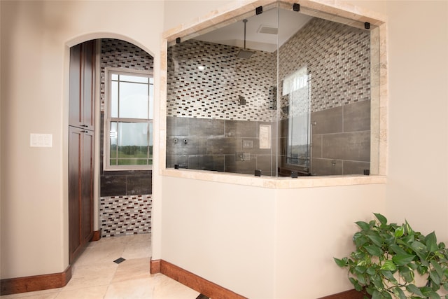 bathroom with tiled shower and tile flooring