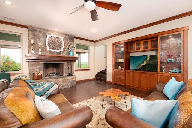 living room with crown molding, ceiling fan, a fireplace, and dark wood-type flooring