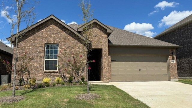 view of front of home featuring central air condition unit, a garage, and a front lawn